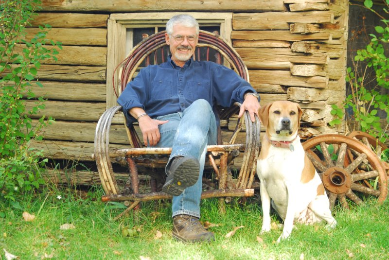 Voice Talent John Drew and his dog, Holli, sitting in front of an 1800's chicken coup in Lander, Wyoming.